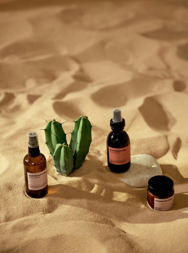 Skincare products artistically arranged in a sandy desert setting with a cactus.